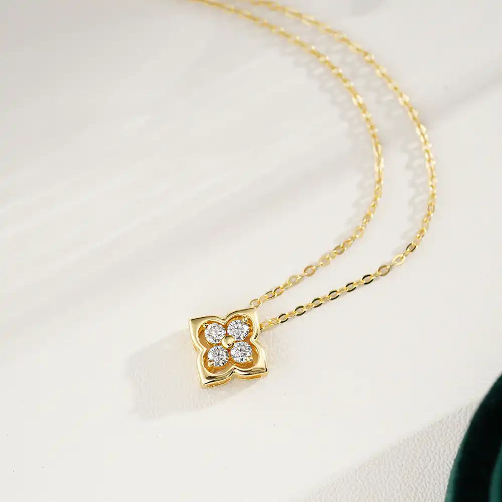 Gold chain necklace with a floral four-stone moissanite pendant on a light background