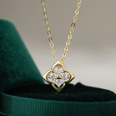 Gold clover-shaped pendant necklace with moissanite stones on green velvet box