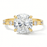 Oval moissanite engagement ring with gold band and side stones on white background