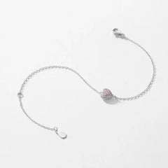 Delicate silver chain bracelet with a pink heart-shaped moissanite charm on white background