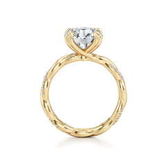 Gold moissanite engagement ring with twisted band and pavé stones against white background