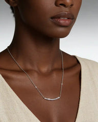 Woman wearing a moissanite bar necklace on a delicate silver chain