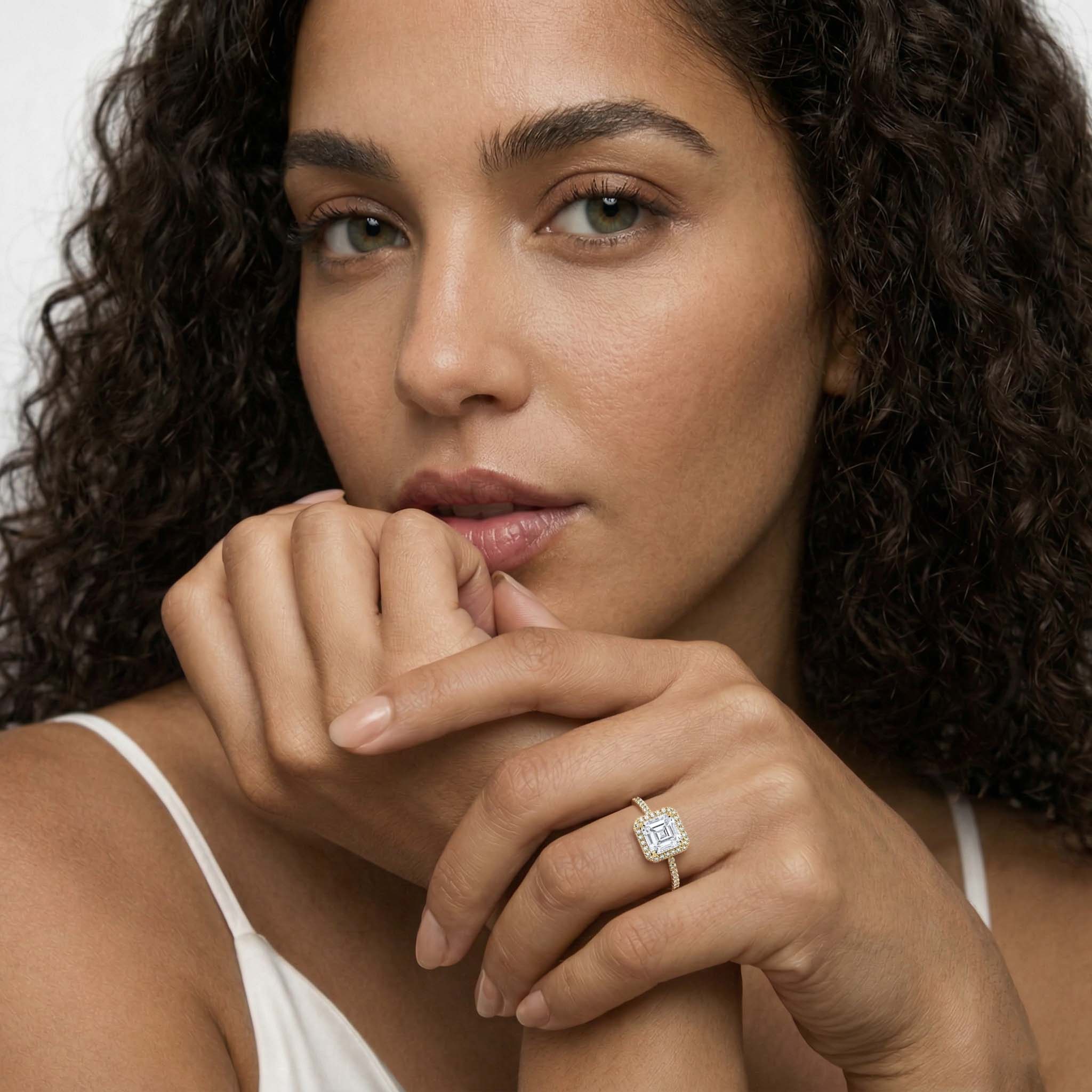 Woman wearing a moissanite halo engagement ring with a square center stone