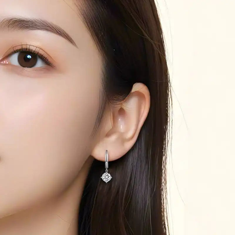 Woman wearing a silver drop earring with a square moissanite stone
