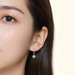 Woman wearing a silver drop earring with a square moissanite stone
