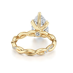Pear-shaped moissanite gold ring with twisted band and diamond accents on white background