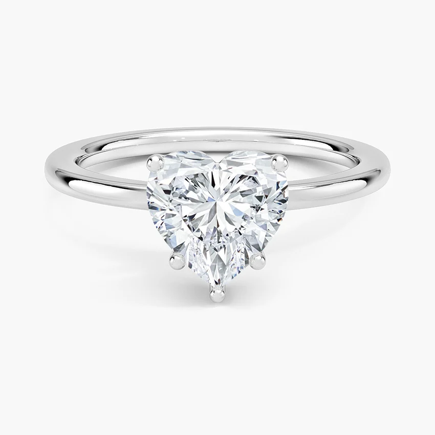 Heart shaped moissanite solitaire ring with a silver band on white background