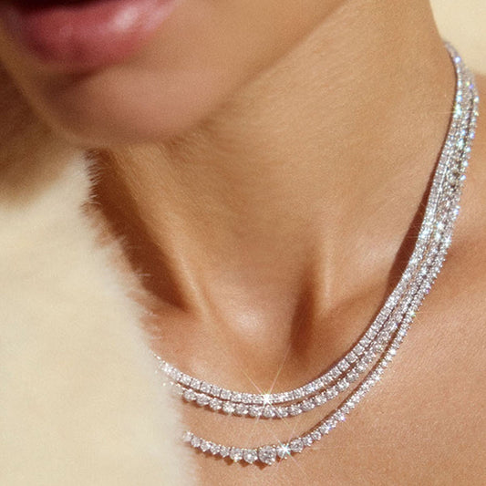 Elegant woman wearing layered moissanite tennis necklaces, sparkling against bare skin