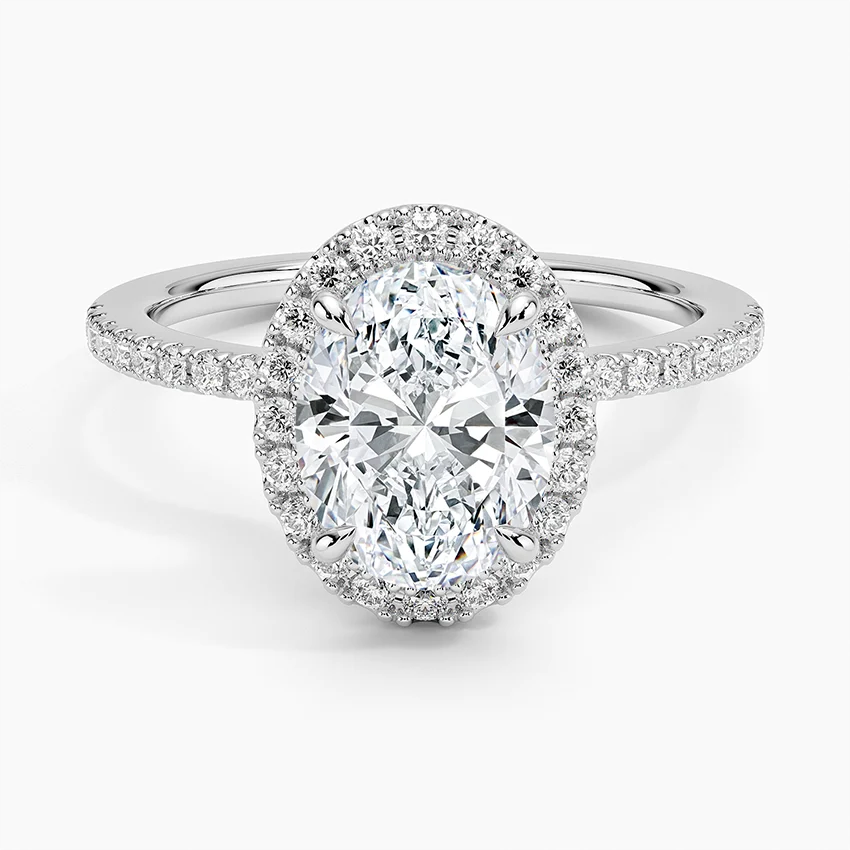 Oval moissanite halo engagement ring with pavé band in white metal, sparkling center stone