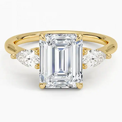Emerald cut moissanite ring with side stones on yellow gold band, luxury jewelry