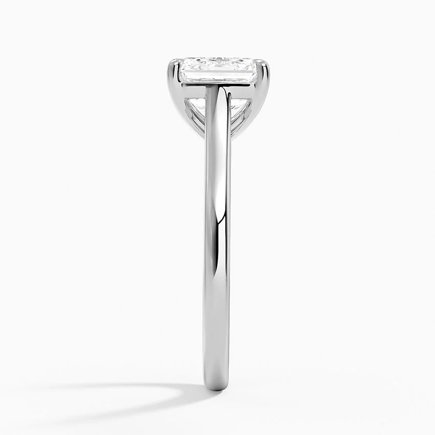 Side view of a solitaire moissanite ring with a slim, polished metal band