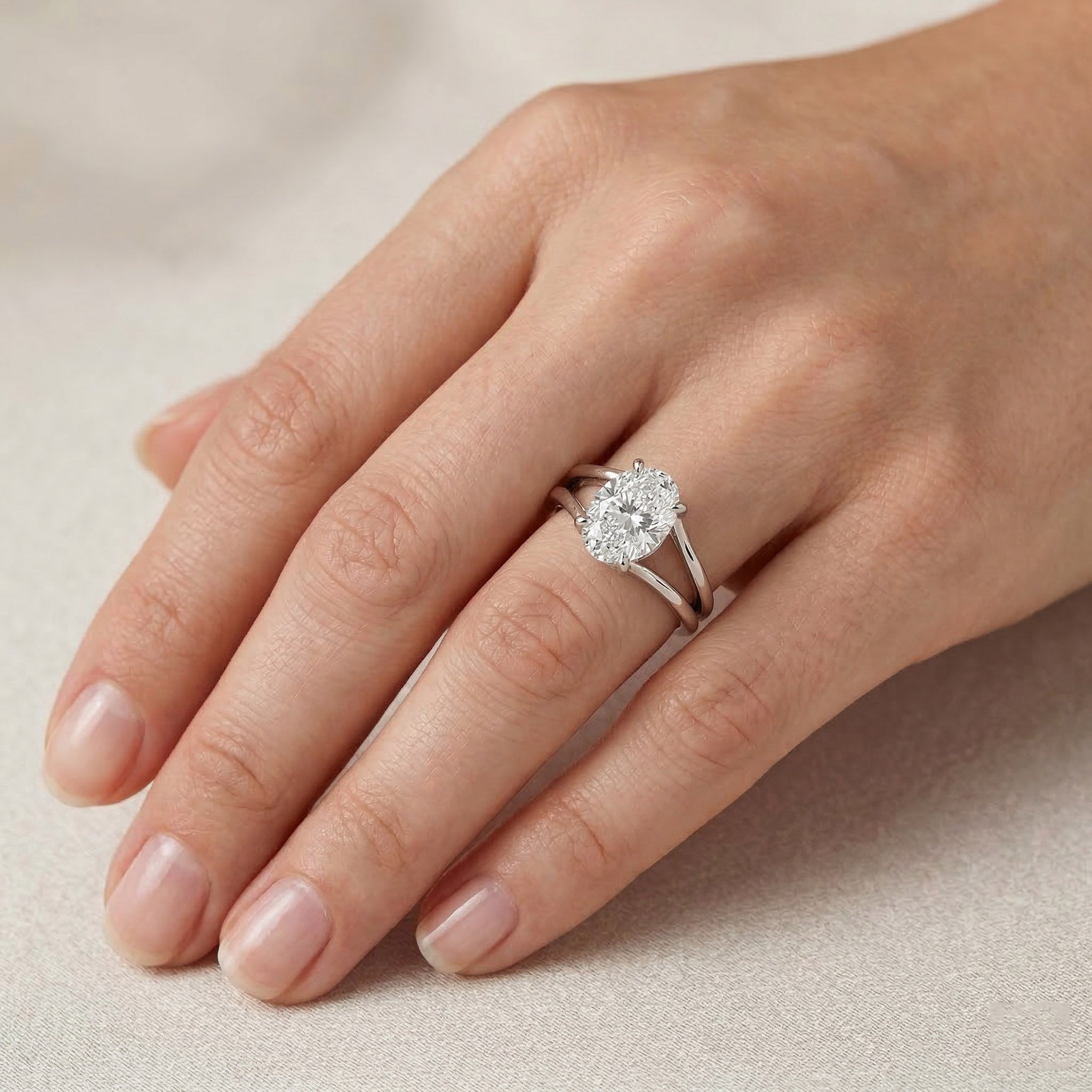 Oval moissanite engagement ring with split shank on hand, silver band jewelry