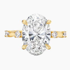 Oval moissanite engagement ring with gold band and side stones on white background