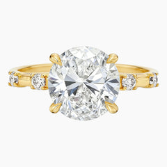 Oval moissanite engagement ring with gold band and side stones on white background