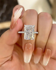 Radiant cut moissanite engagement ring with pave band on hand with long ombre nails
