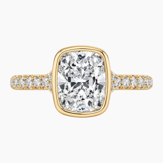 Cushion cut moissanite gold ring with pavé band on white background