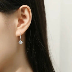 Woman wearing a silver hoop earring with a round moissanite gemstone drop