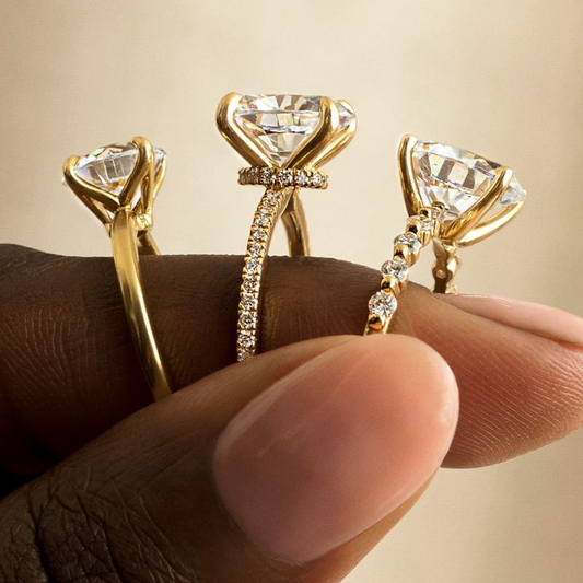Hand holding gold moissanite rings with large center stones and pavé bands, fine jewelry