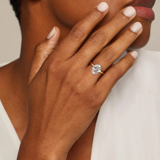 Gold band moissanite engagement ring with round brilliant stone on hand