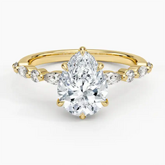 Pear-shaped moissanite ring with side stones on a yellow gold band