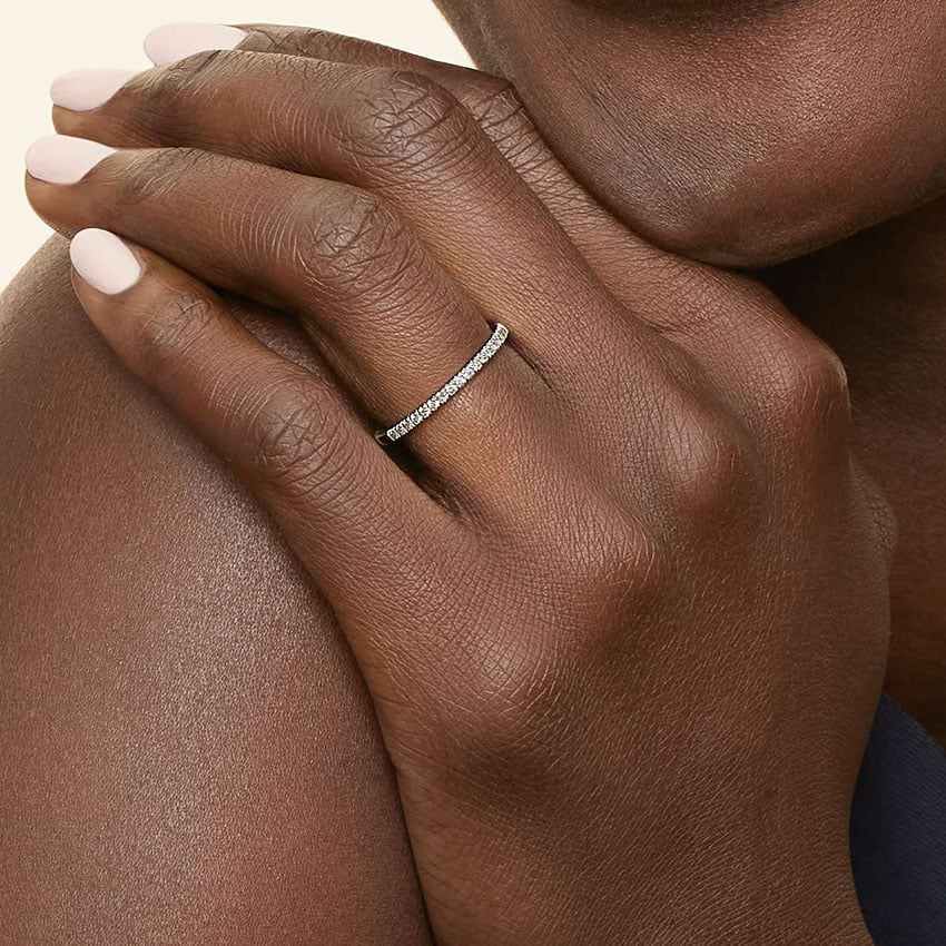 Woman wearing a thin moissanite eternity band ring on her finger, elegant jewelry closeup