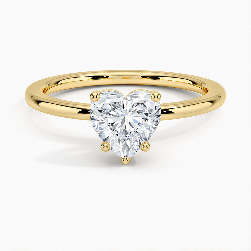 Heart-shaped moissanite solitaire ring with gold band on white background