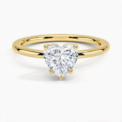 Heart-shaped moissanite solitaire ring with gold band on white background