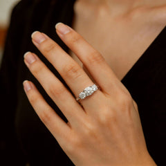 Hand wearing a three-stone moissanite engagement ring with oval cut stones