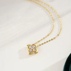 Gold chain necklace with a floral four-stone moissanite pendant on a light background
