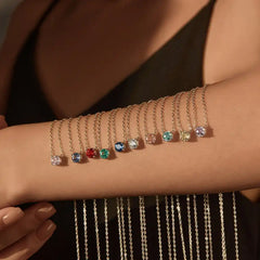 Gold chain bracelets with colorful moissanite gemstones displayed on a woman's arm