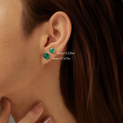 Woman wearing emerald green gemstone stud earrings, 6mm and 8mm size comparison