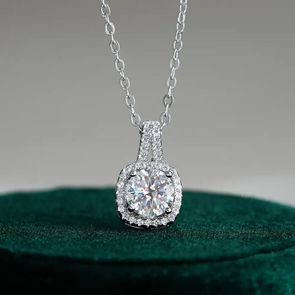 Round moissanite halo pendant necklace in silver with pavé setting on a green surface