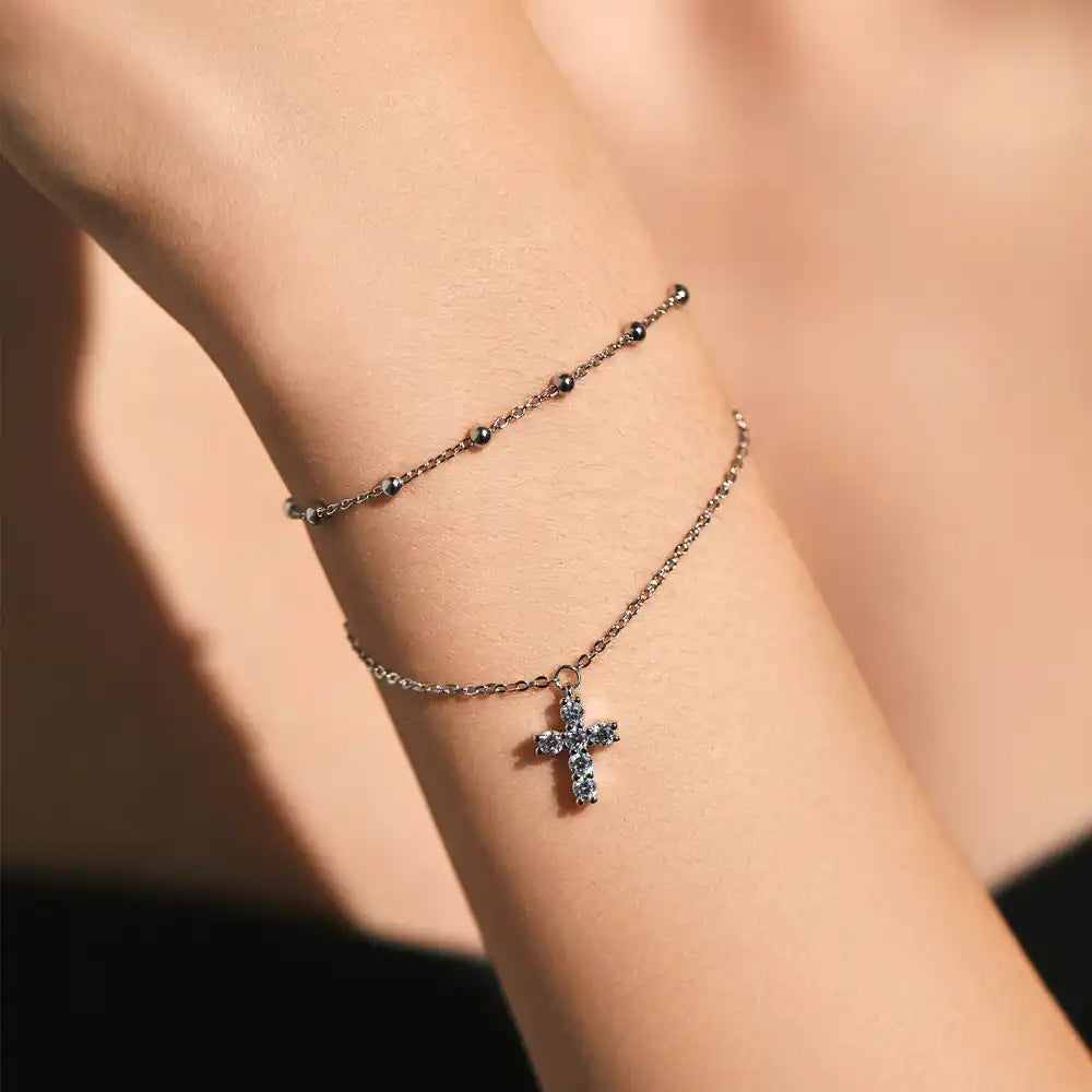 Moissanite cross pendant bracelet on wrist with delicate silver chain jewelry