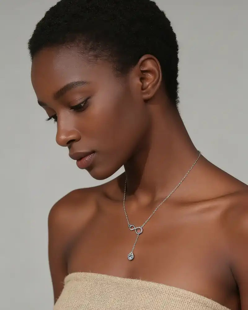 Woman wearing elegant moissanite pendant necklace on bare shoulders, minimal background