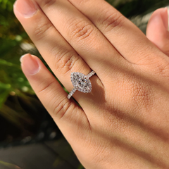 Marquise cut moissanite halo engagement ring with pavé band on hand in natural light