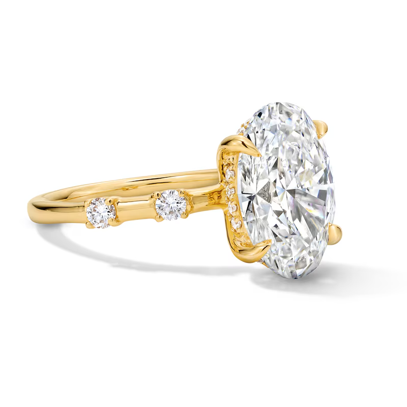 Oval moissanite solitaire ring in yellow gold with side accent stones