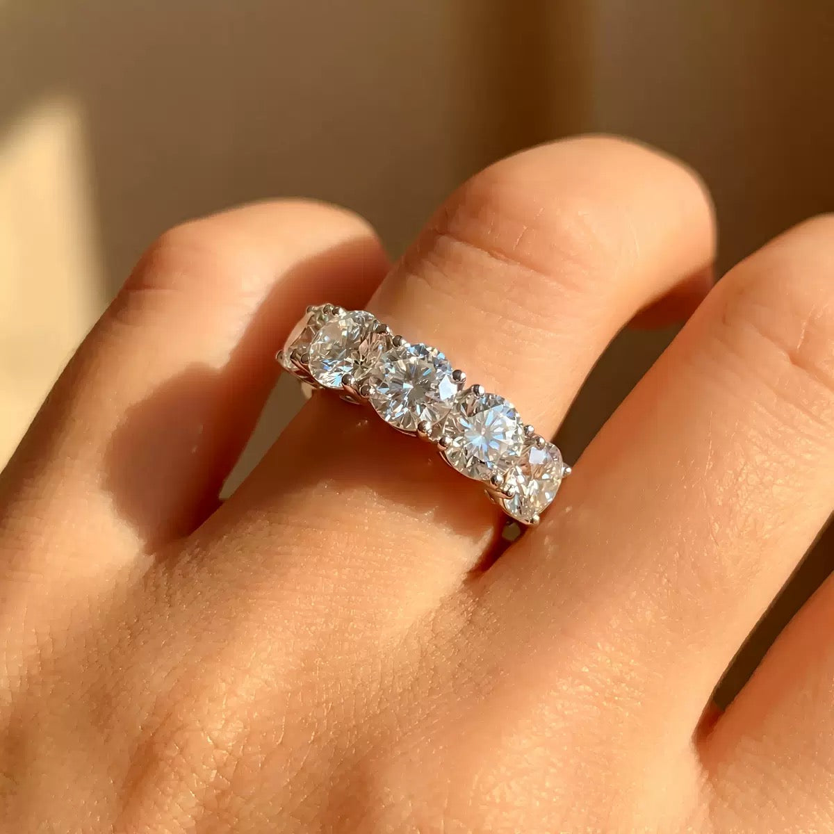 Moissanite eternity band with five round stones on a hand, sparkling in natural light