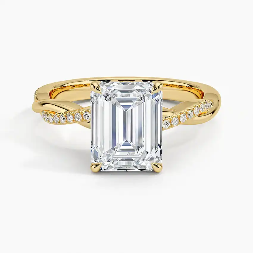 Emerald cut moissanite engagement ring with twisted gold band and pavé side stones