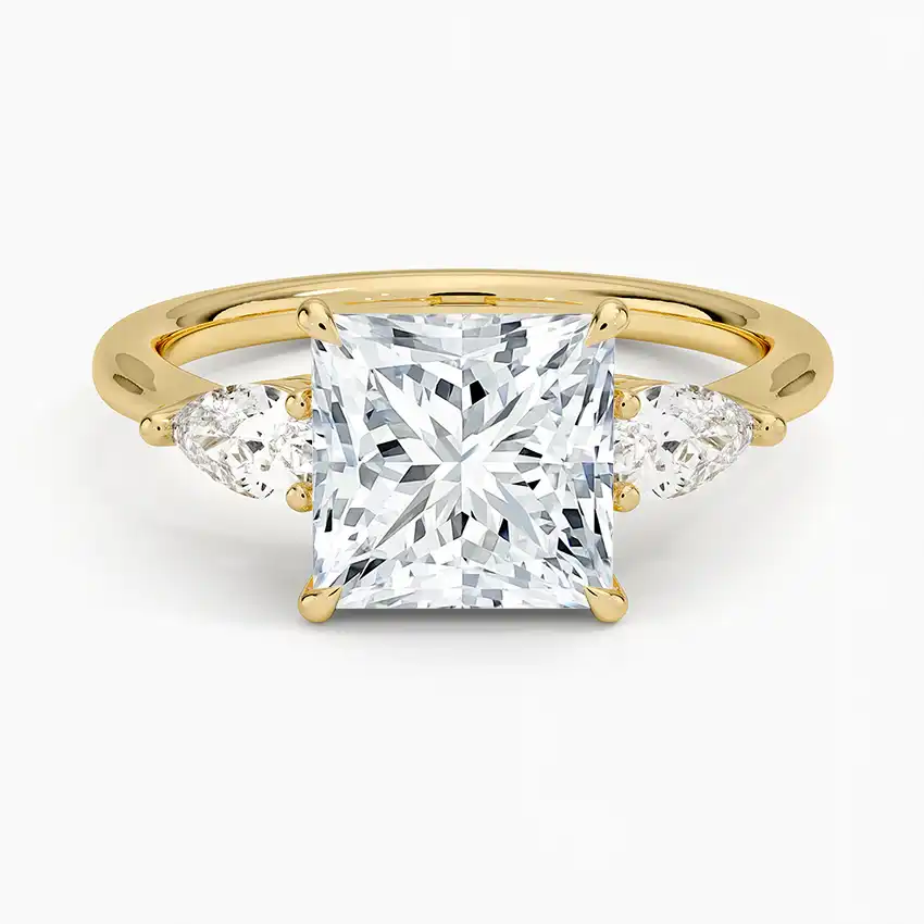 Princess cut moissanite three-stone ring with pear side stones in yellow gold setting