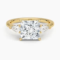 Princess cut moissanite three-stone ring with pear side stones in yellow gold setting