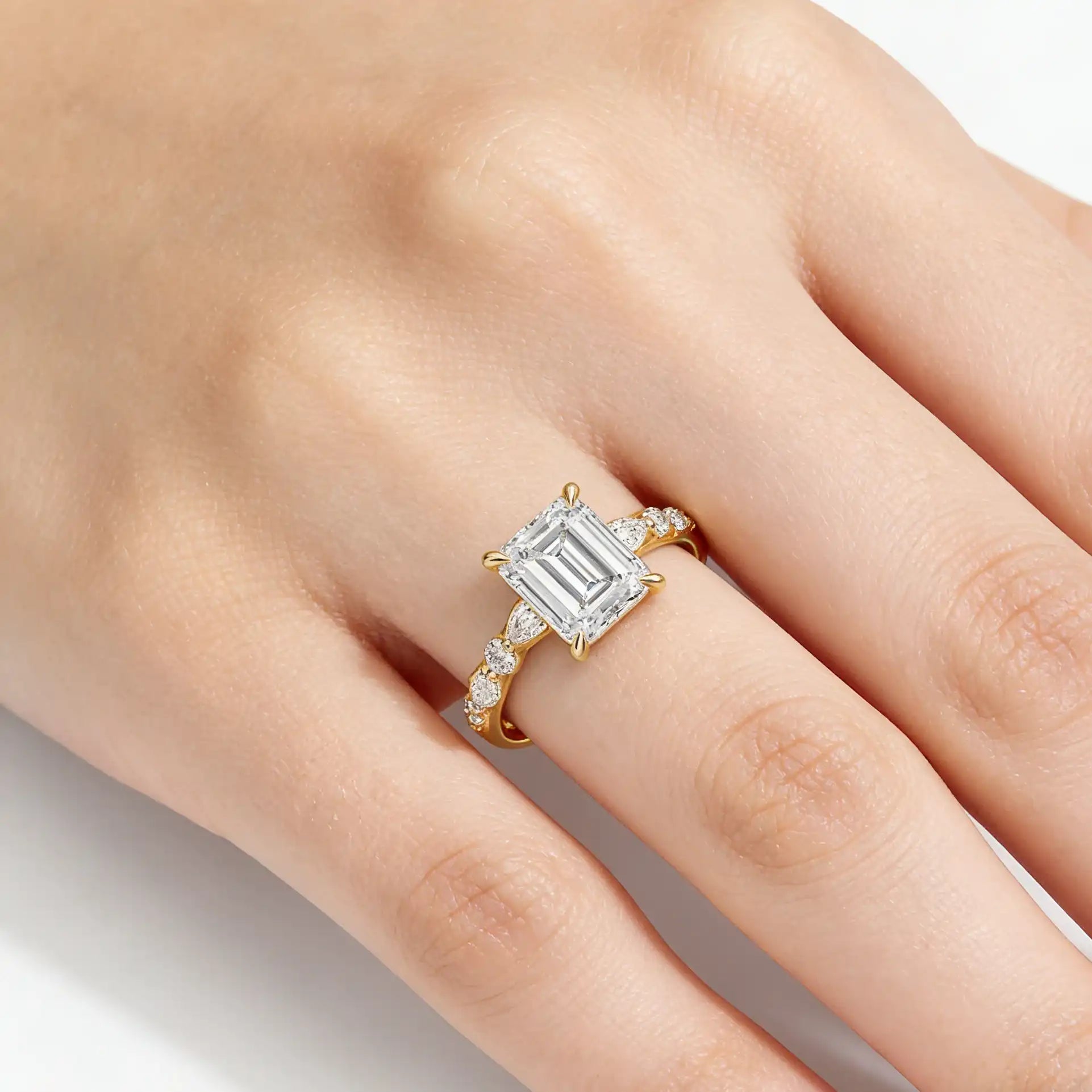 Emerald cut moissanite gold ring with side stones on hand