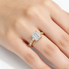 Emerald cut moissanite gold ring with side stones on hand