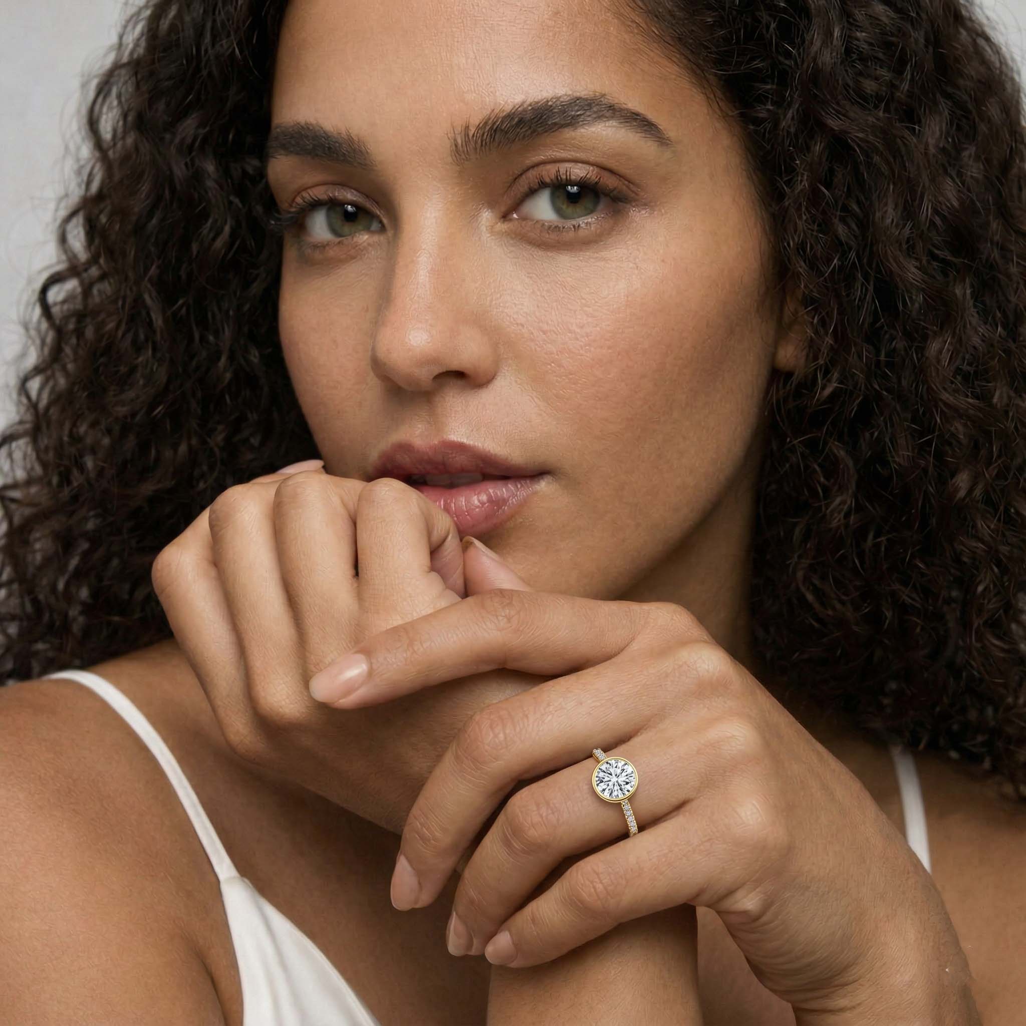 Woman wearing a round moissanite engagement ring with pavé band