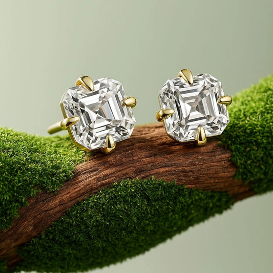 Asscher cut moissanite stud earrings with gold prongs on textured green branch