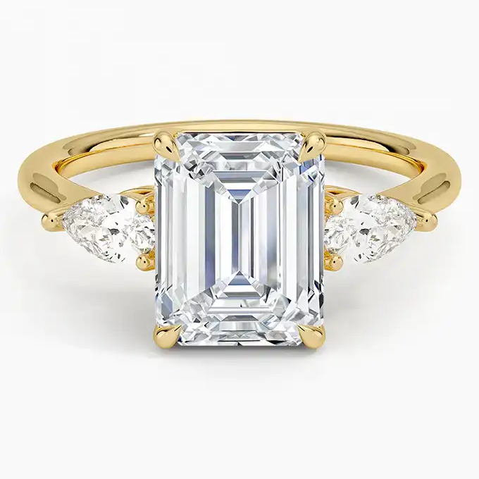Emerald cut moissanite ring with side stones on yellow gold band, luxury jewelry