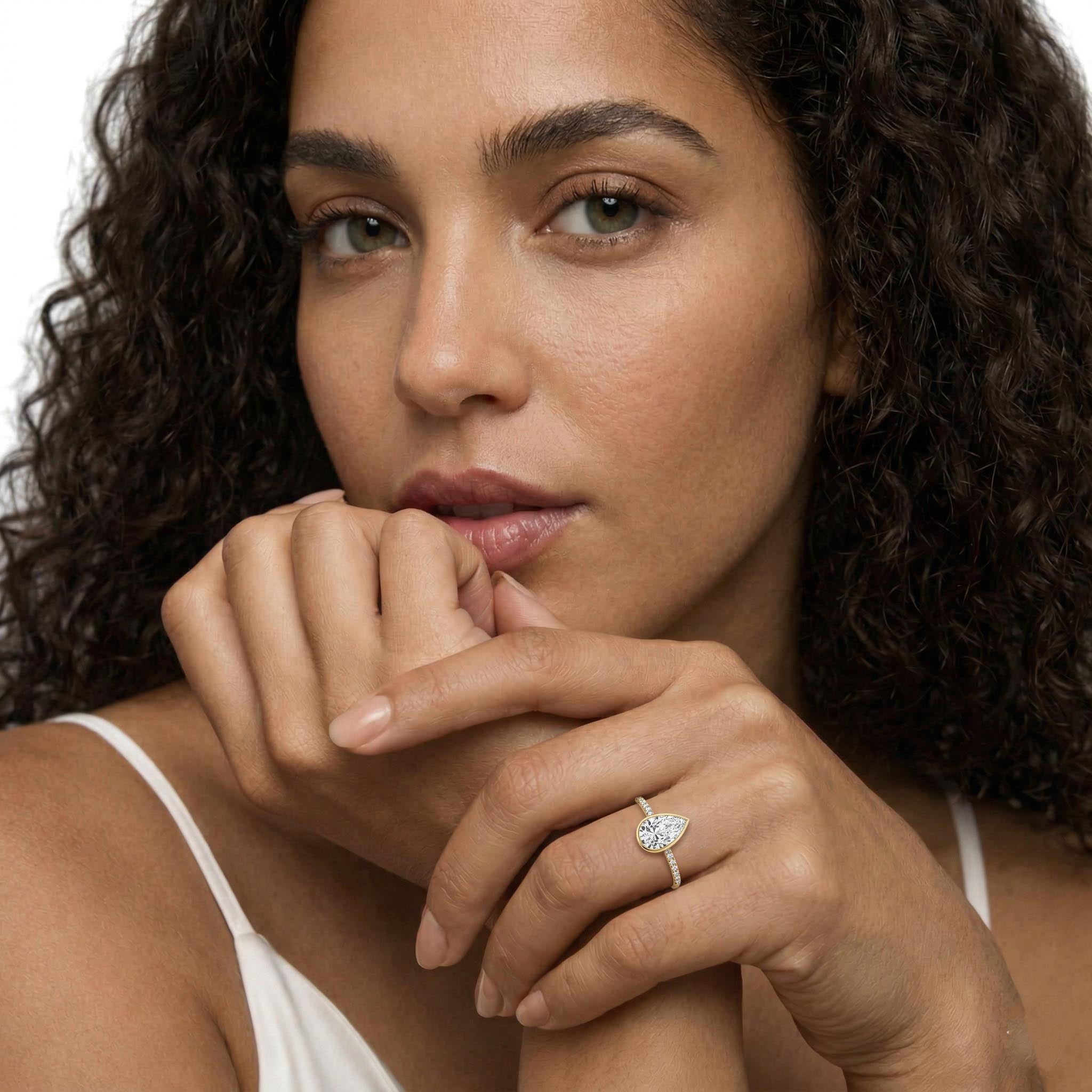 Woman wearing a pear-shaped moissanite engagement ring on her finger