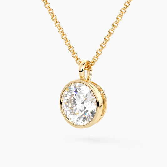 Gold chain necklace with round moissanite pendant in bezel setting on white background.