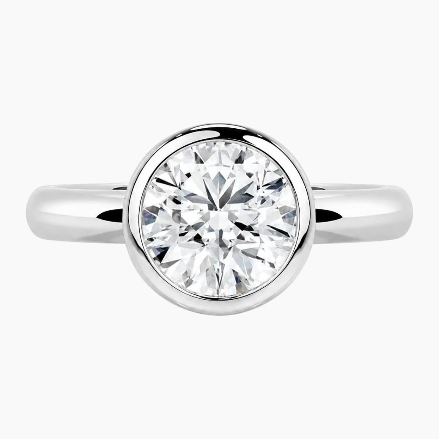 Round bezel moissanite engagement ring with a polished 2.6mm yellow gold band