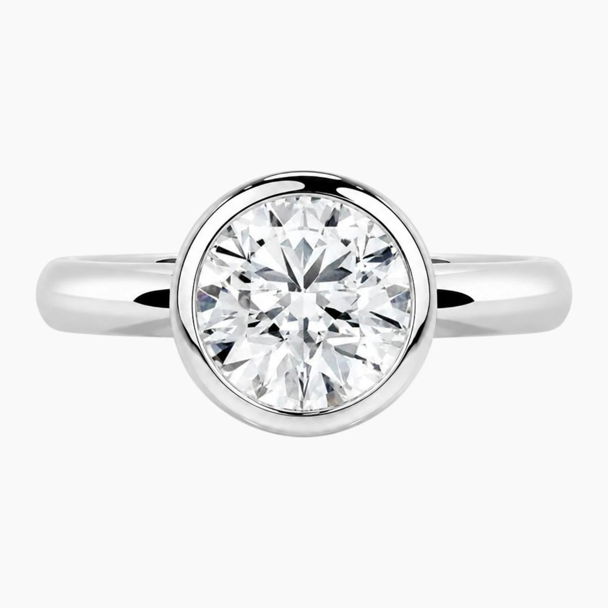 Round bezel moissanite engagement ring with a polished 2.6mm yellow gold band