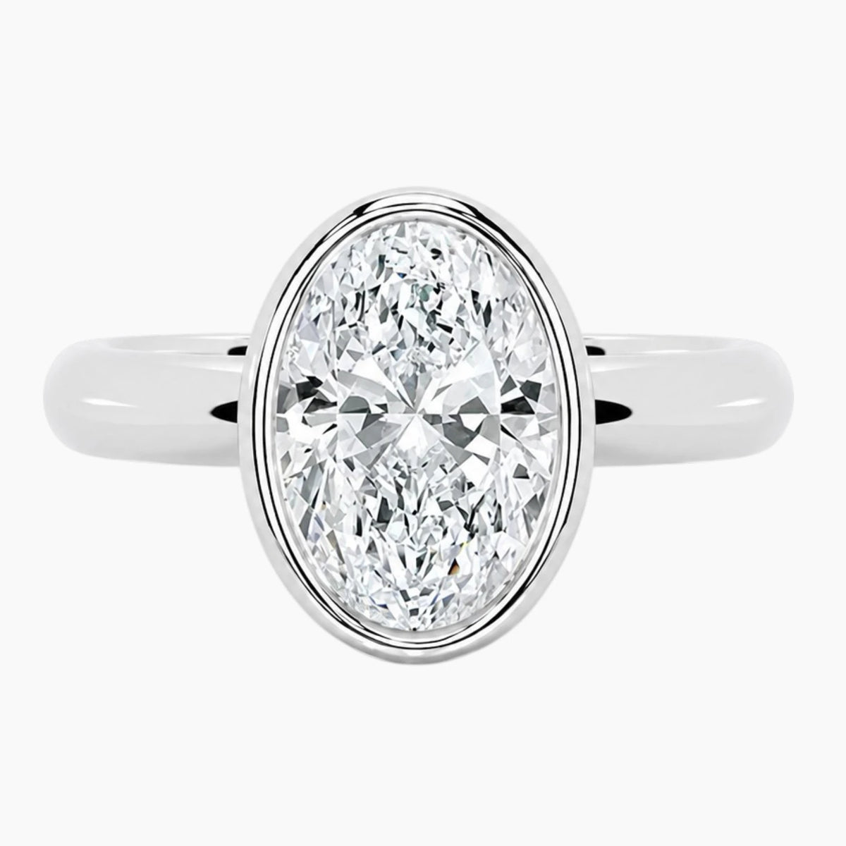 Oval bezel moissanite ring featuring a brilliant oval-cut stone and polished 2.6mm yellow gold comfort-fit band.